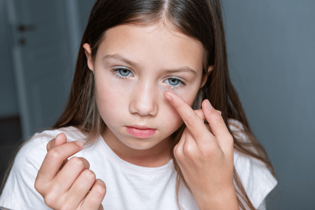 a little girl putting in a contact lens