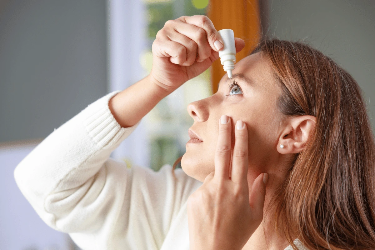 a young woman putting in eye drops for dry eyes