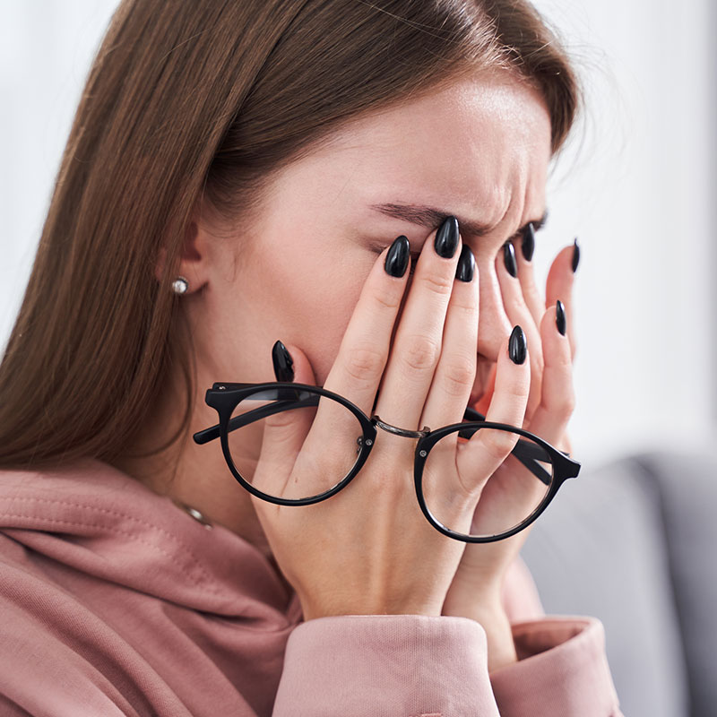Woman looking closely at her eyes in a bathroom mirror, relief of dry eye discomfort.