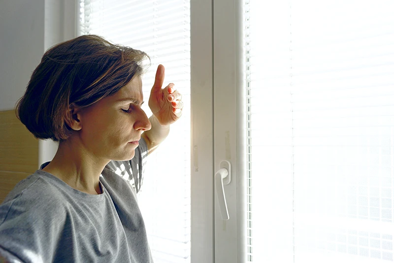 a woman shielding her eyes from window light