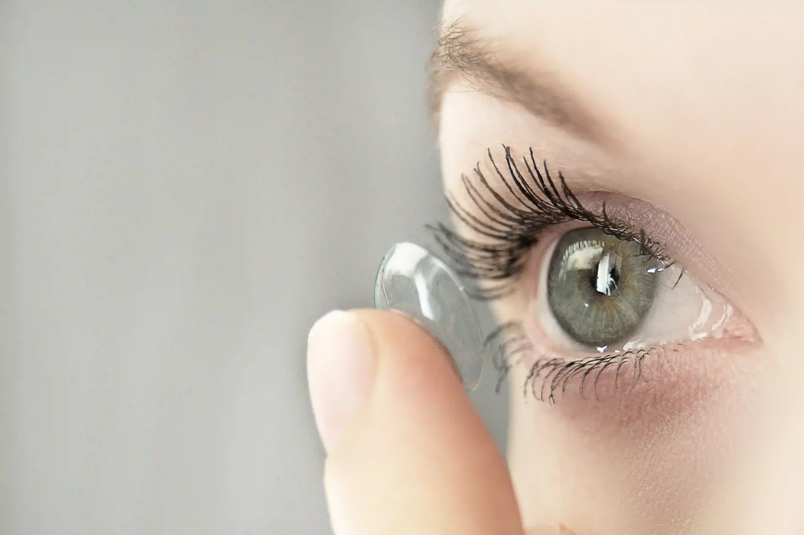 close-up of person placing contact lens on eye